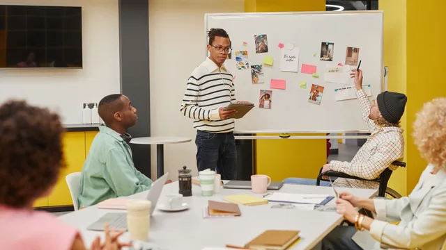 A diverse team engaged in a collaborative meeting around a whiteboard in a modern office setting. Rehearsing a corporate communications correction on synthetic copy