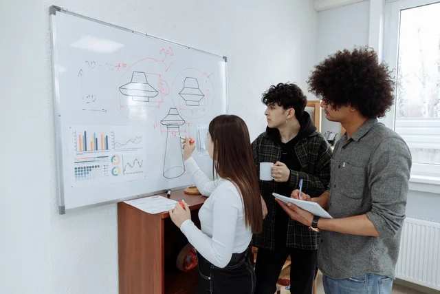 Young professionals brainstorming and designing a product prototype on a whiteboard. Designing a corporate communications dashboard with four panes and a data-health rail