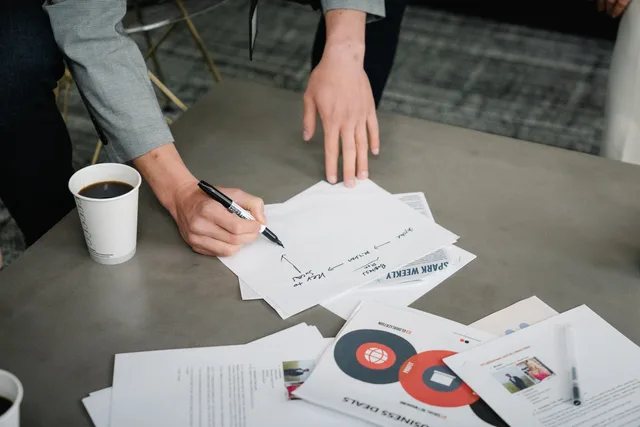 Team members reviewing and annotating business documents during a meeting. How to run a corporate communications supplier comparison